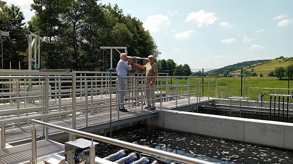 Zwei Herren besichtigen ein Abwasserbecken.