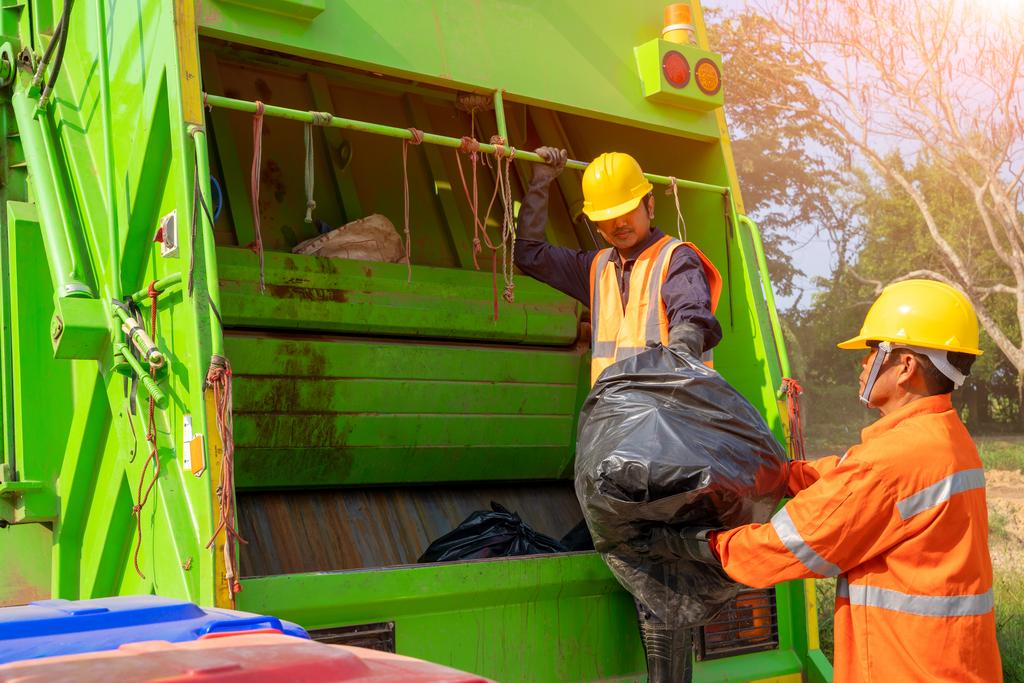 Two garbage men working together on emptying dustbins for trash