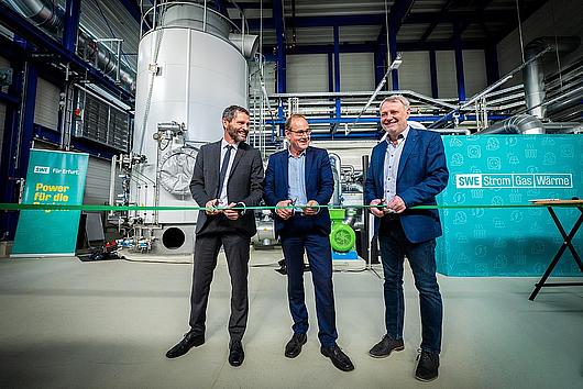 Minister schneidet ein Band durch.