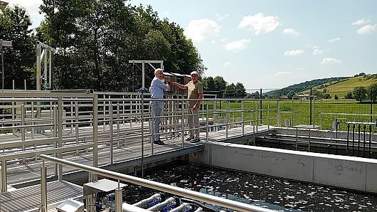 Zwei Herren besichtigen ein Abwasserbecken.